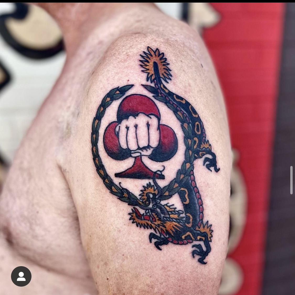 Tattoo of a dragon and a fist on a man's shoulder from top tattoo shop in Dallas TX