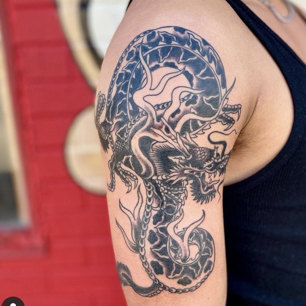 Large dragon tattoo on a man's arm and shoulder in Dallas