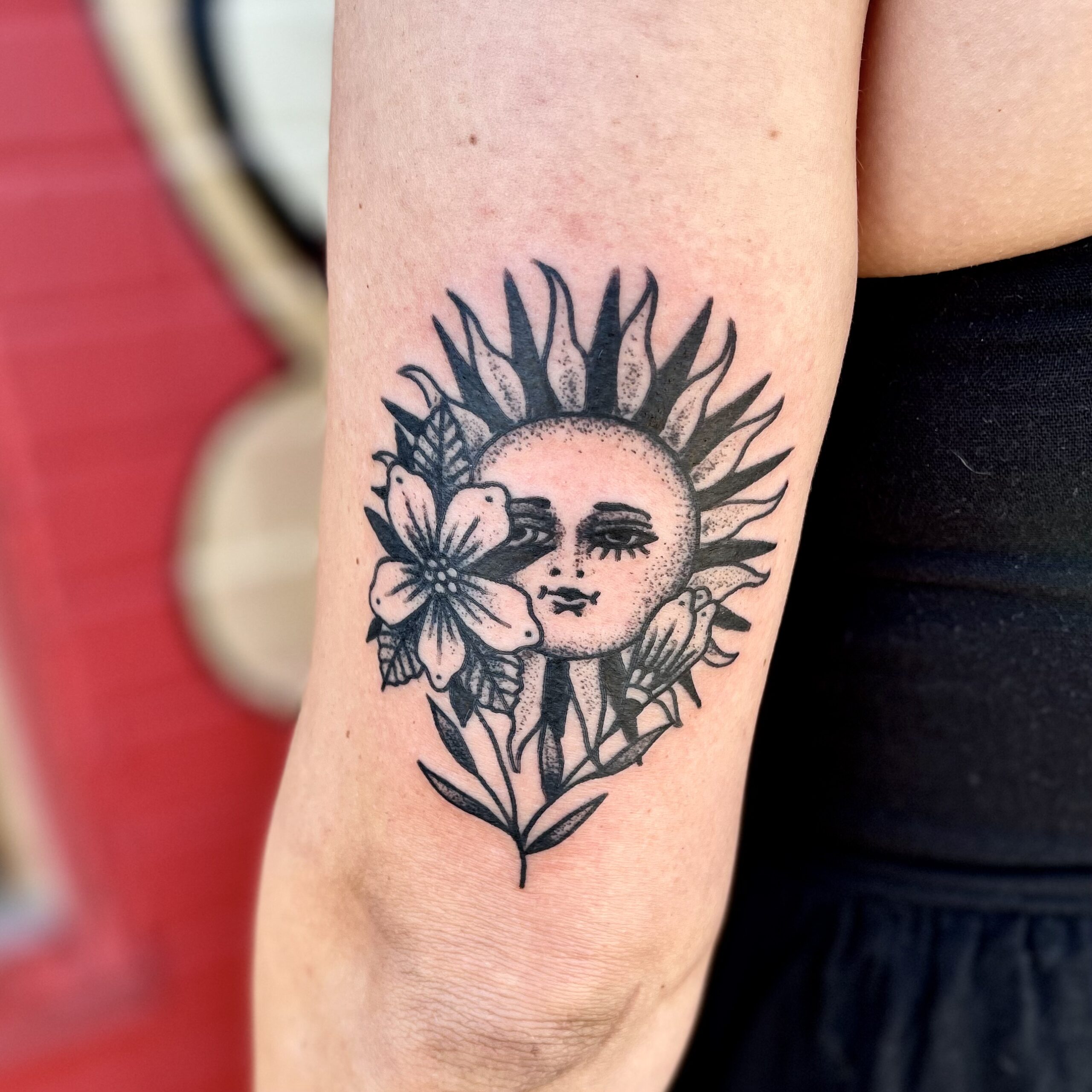 Tattoo of a flower and a sun on a woman's arm from best tattoo shops in dallas