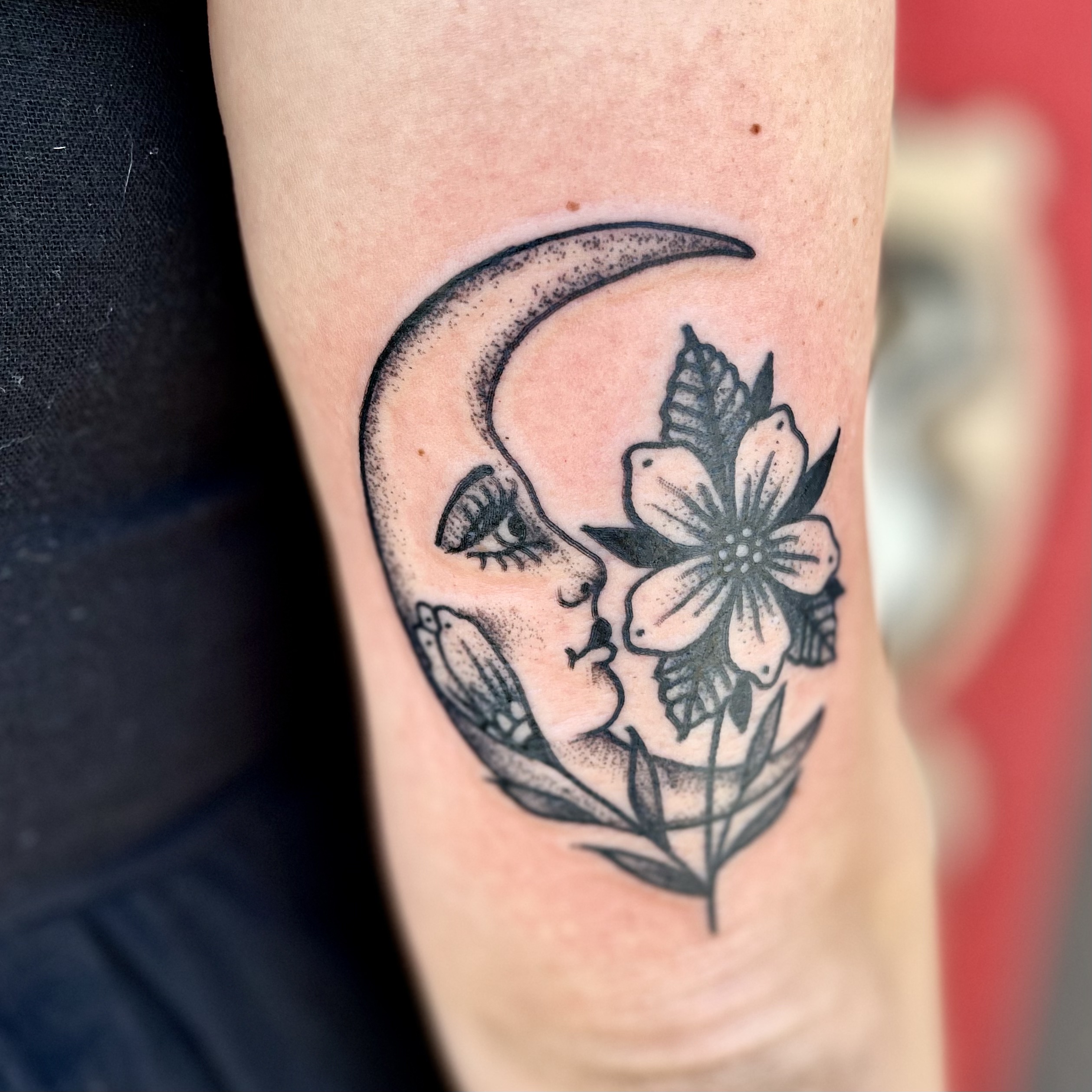 Tattoo of a moon on the back of a mans arm