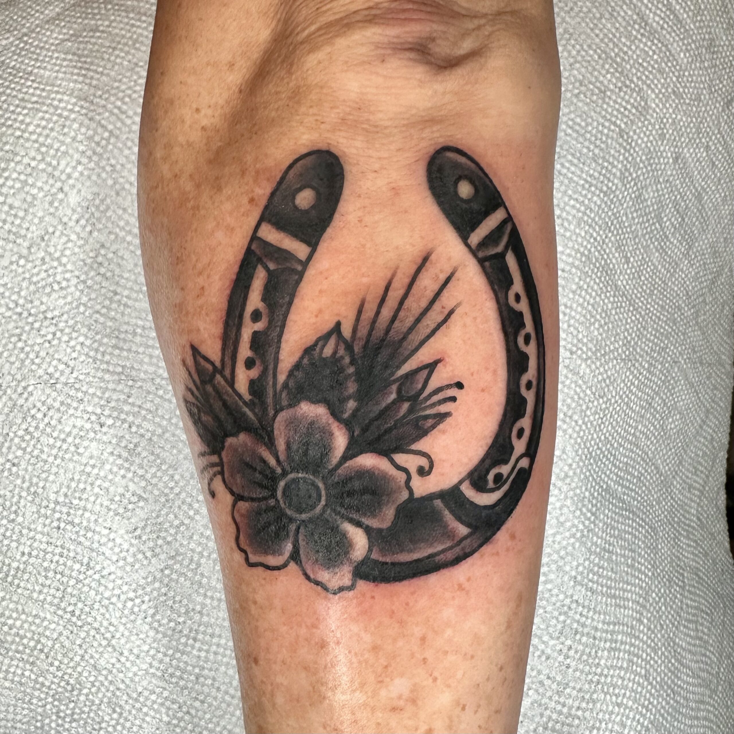 tattoo of a horseshoe with a flower on it