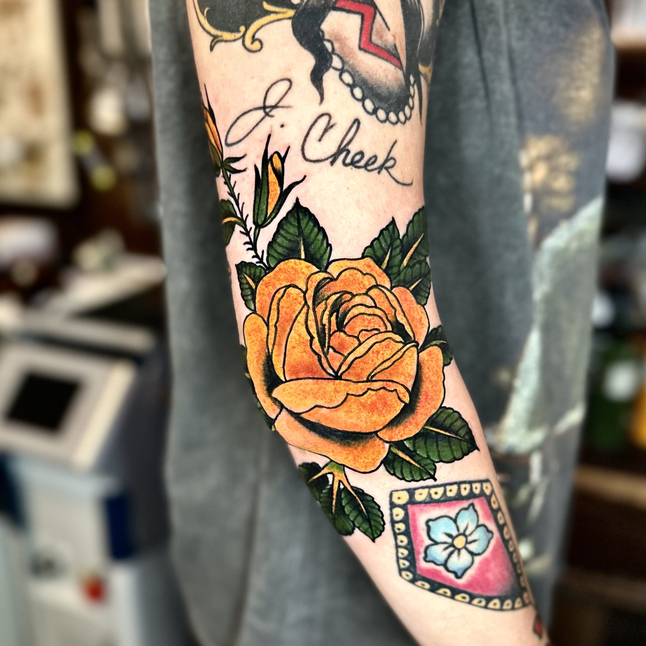 tattoo of a yellow flower with green leaves on an arm