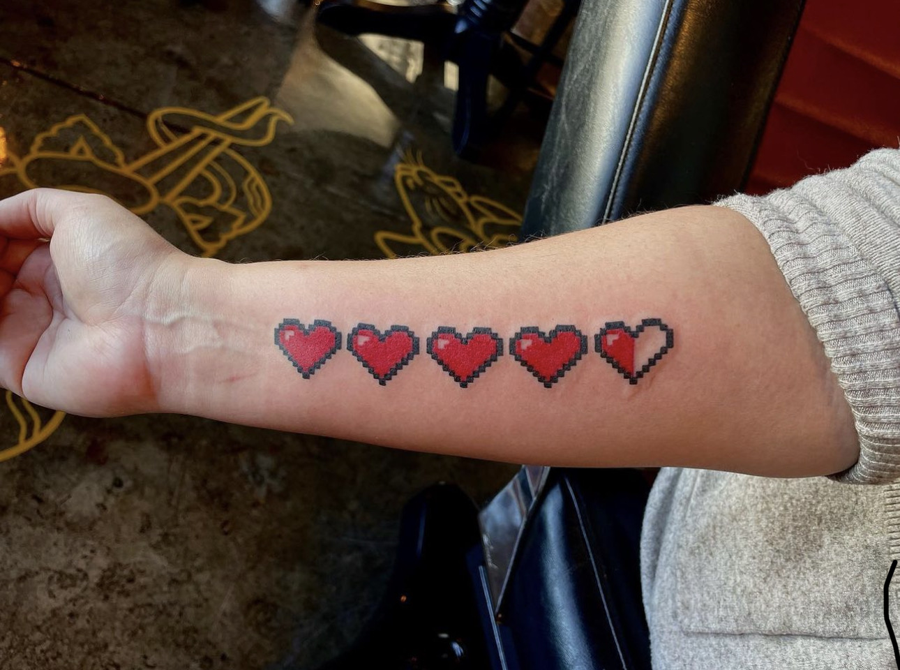 Tattoo of 5 videogame hearts on an arm
