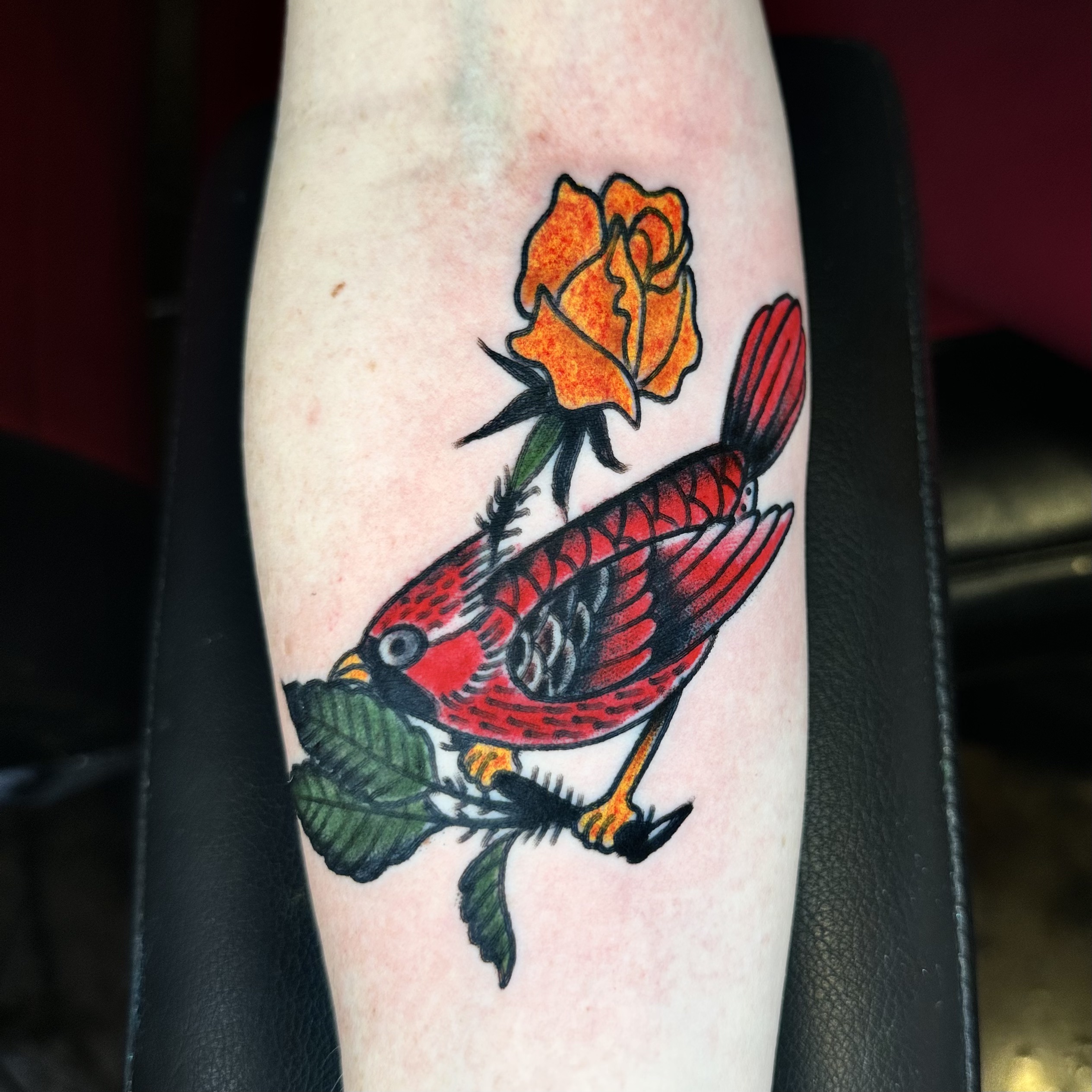Tattoo of a red bird and an orange flower