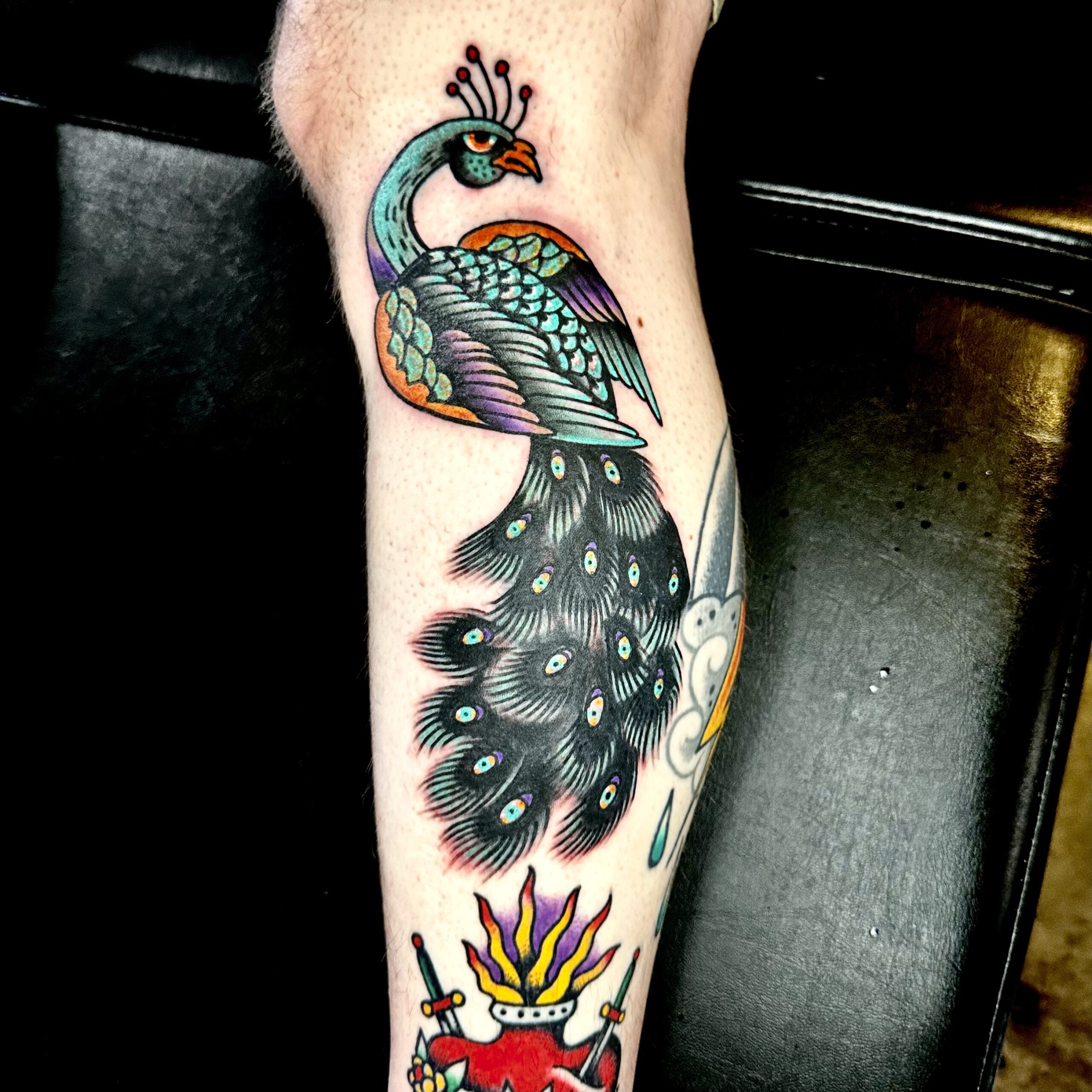 Tattoo of a peacock on a man's leg