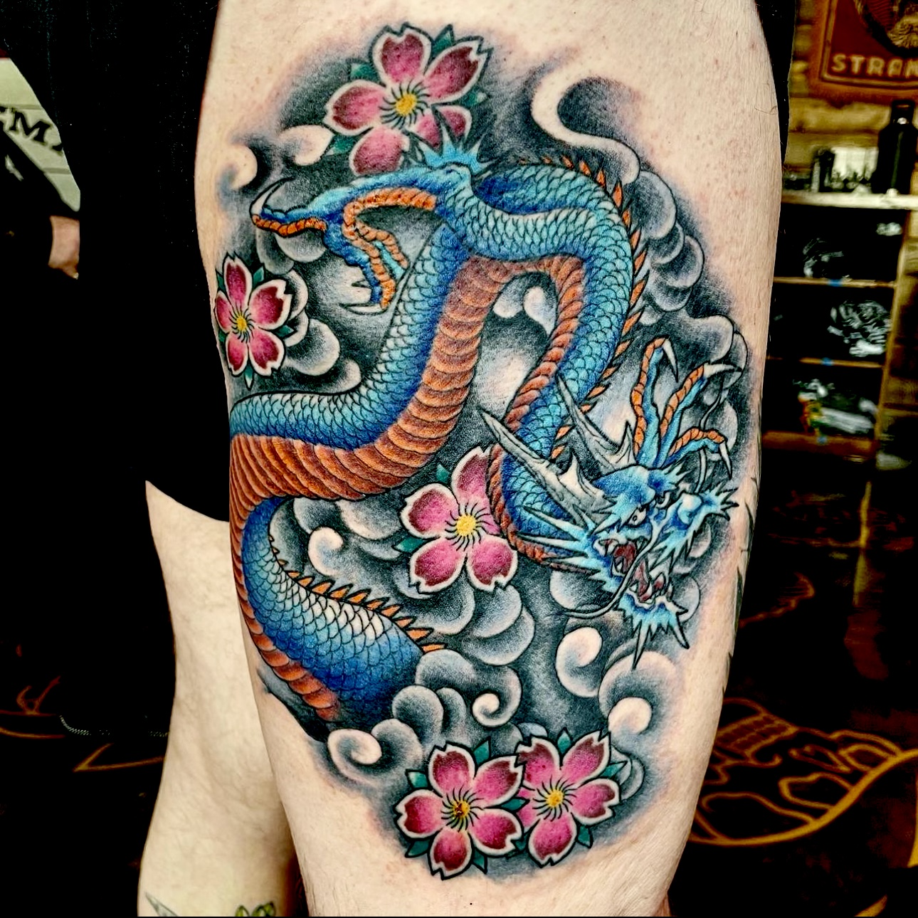 Tattoo of a blue dragon and pink flowers