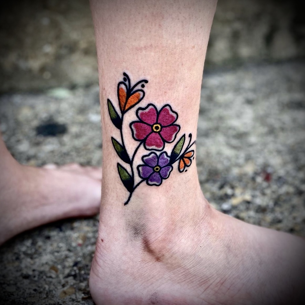 Tattoo of a flower on an ankle