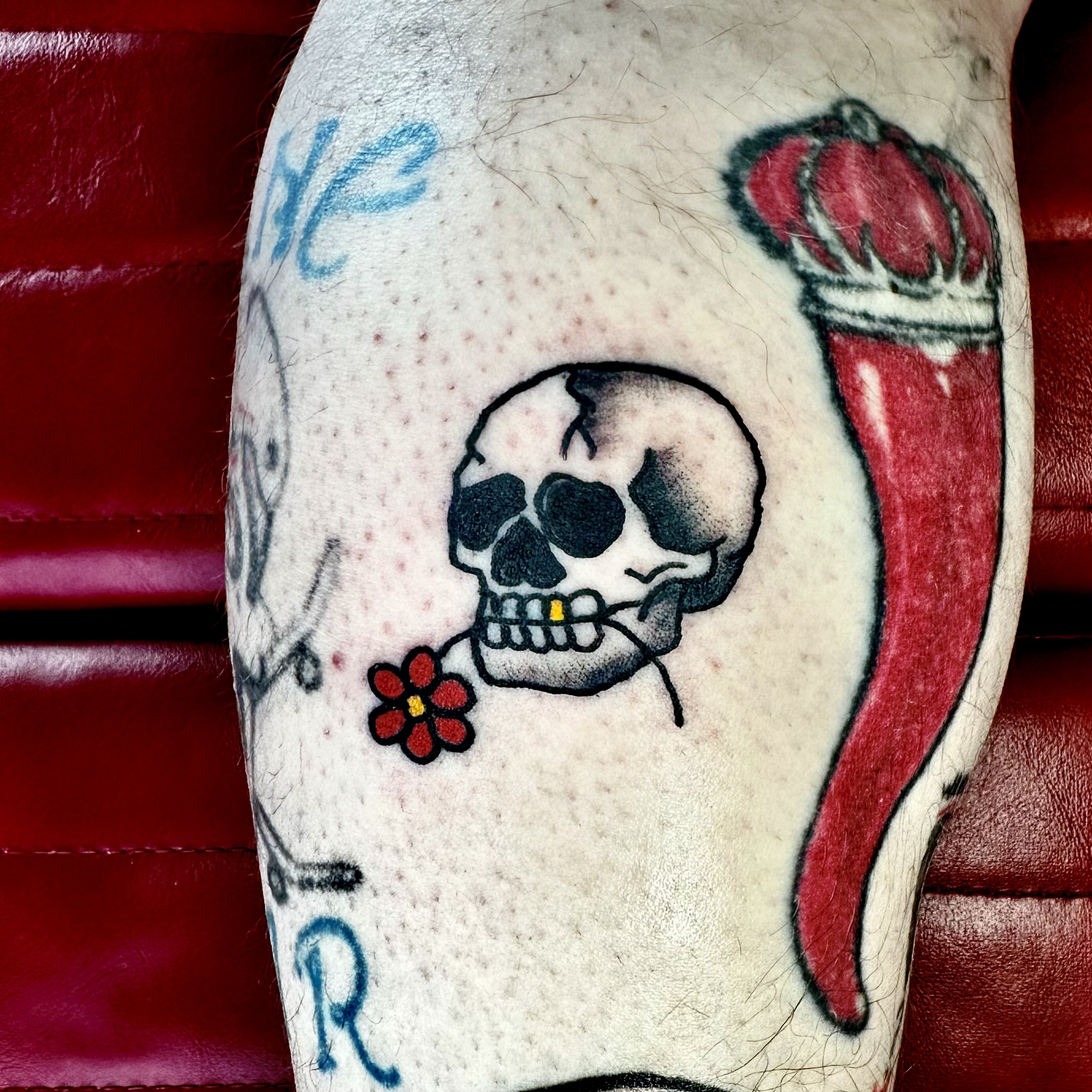 Tattoo of a skull with a red flower and a gold tooth